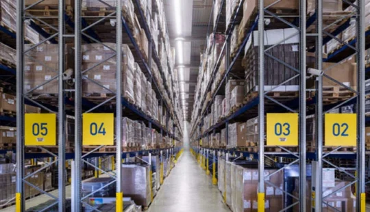 Interiör av logistikanläggning med pallställ och lagergång.