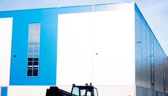 Exteriör av logistikhall med ljus fasad och blå accent.